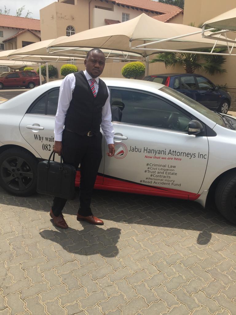 Jabu Hanyani standing beside the Jabu Hanyani Attorneys Inc branded vehicle in Midrand, with practice areas listed on the door: Criminal Law, Civil Litigation, Trust and Estate, Contracts, Personal Injury, Road Accident Fund